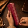 Tannor Irodori hand-woven cowhide long wallet in Fuchsia, side view styled in a lifestyle setting