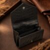 Tannor crocodile-embossed leather envelope wallet in black, open, showing the note compartment and coin pocket