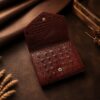Tannor crocodile-embossed leather envelope wallet in chocolate brown, open, showing the note compartment and coin pocket
